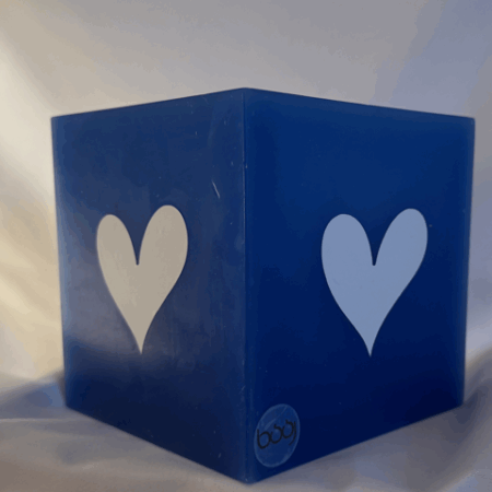 Photophore bleu à cœurs blancs – Collection boo-j Photophore bleu en cire minérale, cube d’environ 12 cm de côté, orné de deux cœurs blancs. Création artisanale boo-j, laissant passer la lumière avec douceur.