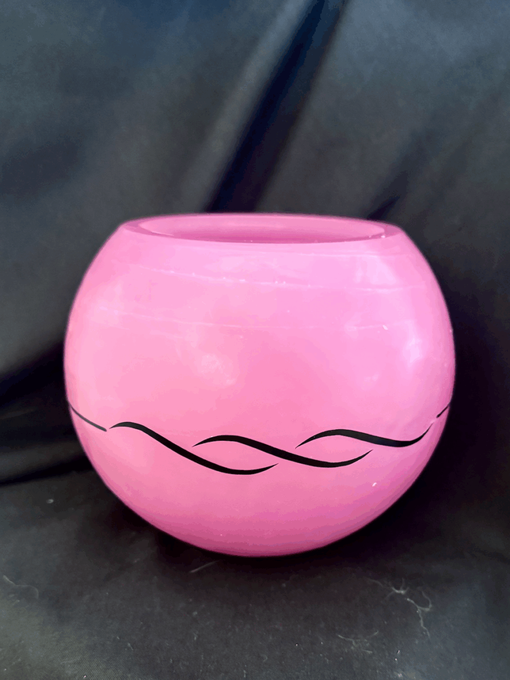 Photophore sphérique rose en cire minérale translucide, décoré d’un motif de vagues noires, fait main dans le canton de Vaud.