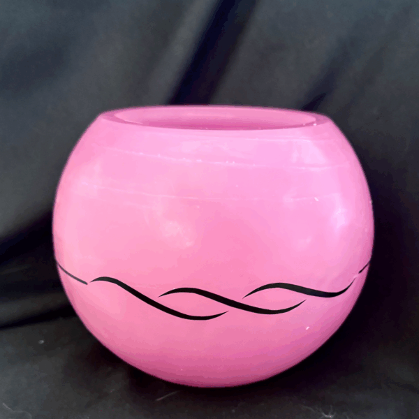 Photophore sphérique rose en cire minérale translucide, décoré d’un motif de vagues noires, fait main dans le canton de Vaud.