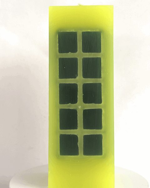 Bougie jaune citron fluo avec incrustations vert foncé.
