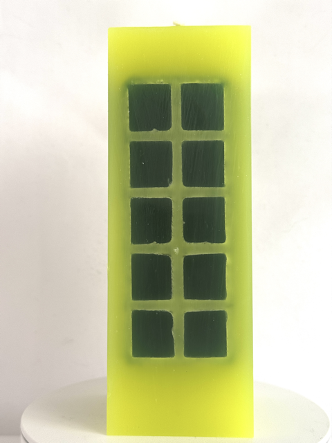 Bougie jaune citron fluo avec incrustations vert foncé.