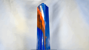 Bougie haute à pans bleus, orange et blanc évoquant des escaliers