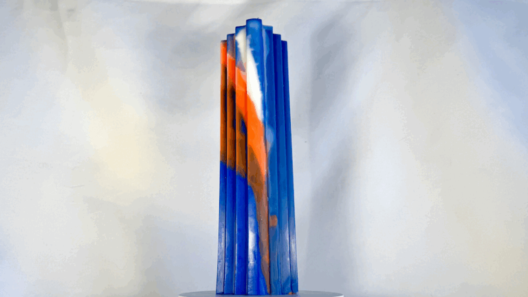 Bougie haute à pans bleus, orange et blanc évoquant des escaliers