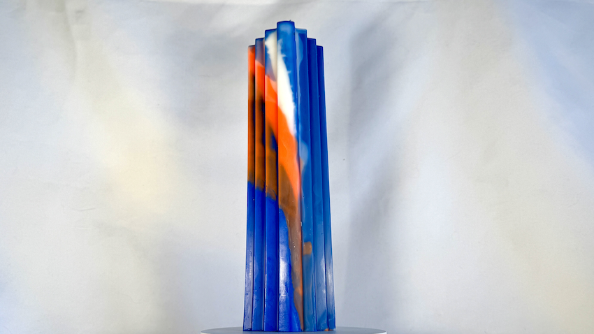 Bougie haute à pans bleus, orange et blanc évoquant des escaliers