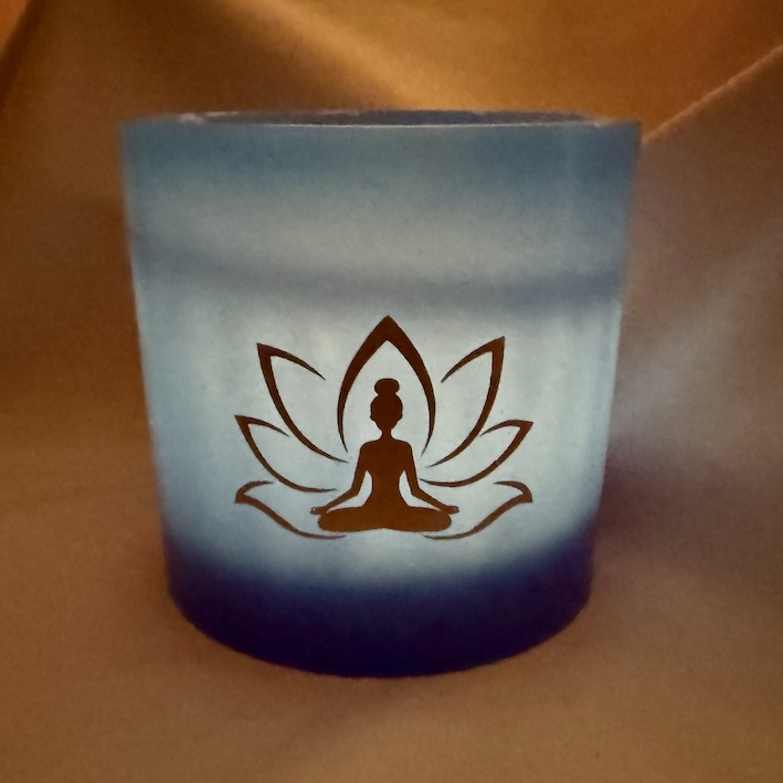 Photophore bleu lotus – femme méditant Photophore bleu en cire artisanale, diamètre 12 cm, décoré de deux motifs lotus dorés avec silhouette de femme méditant.