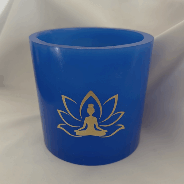 Photophore bleu lotus – femme méditant Photophore bleu en cire artisanale, diamètre 12 cm, décoré de deux motifs lotus dorés avec silhouette de femme méditant.