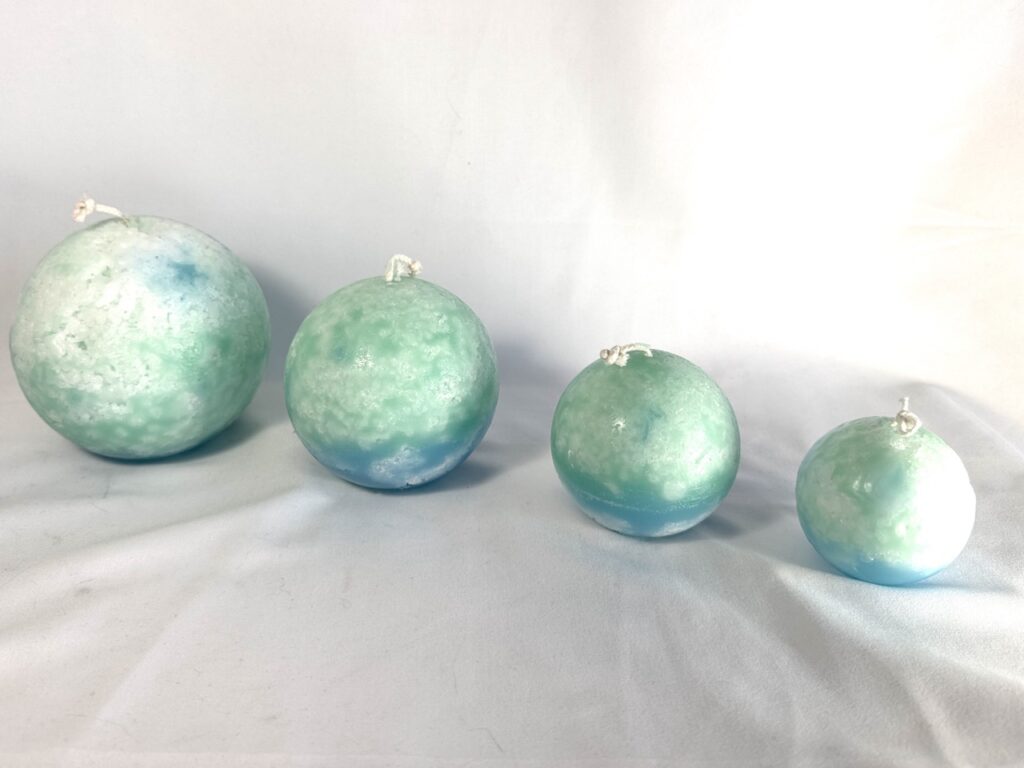 Vue d’ensemble de la collection Europa boo-j : quatre sphères artisanales en cire minérale, aux teintes vert d’eau, turquoise et bleu profond