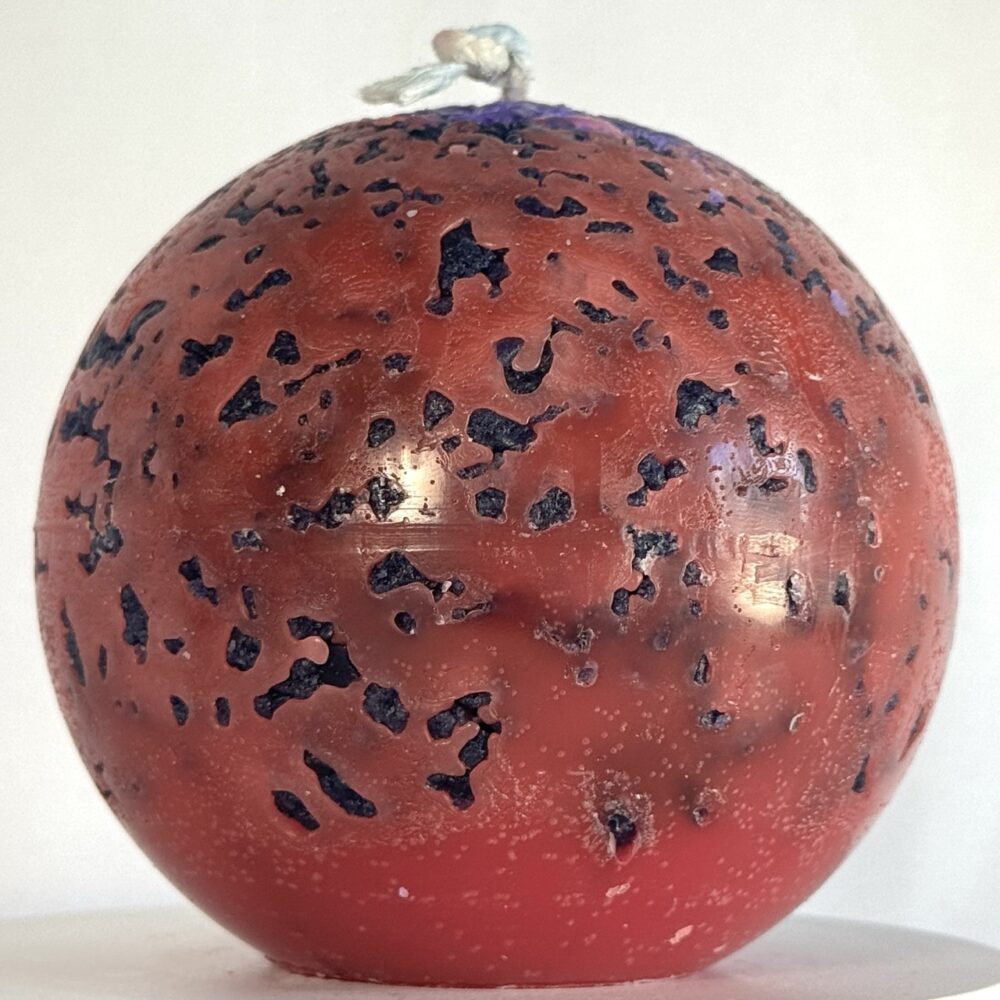 Mercury – sphère volcanique 10 cm – cire minérale rouge et violet Sphère de 10 cm rouge fluo avec éclats violets, effet brûlé, série Mercury