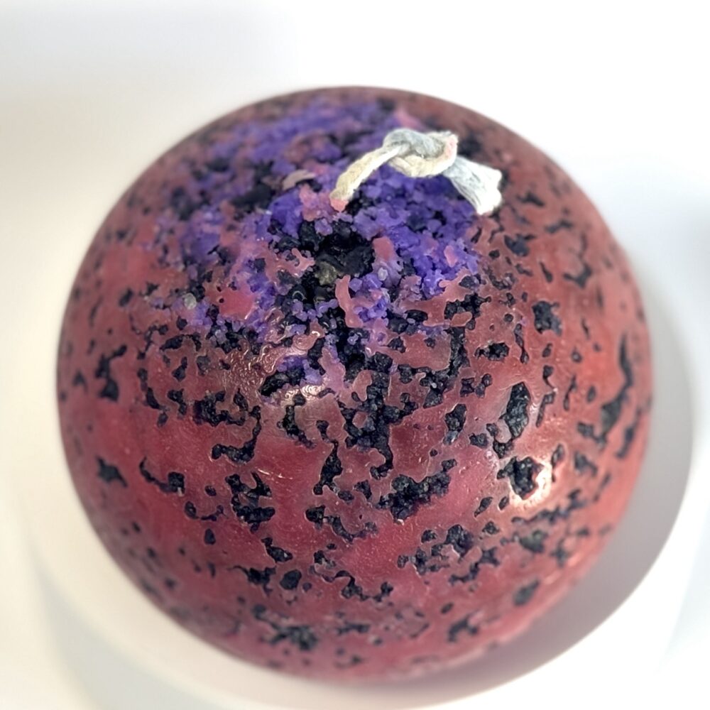 Mercury – sphère volcanique 10 cm – cire minérale rouge et violet Sphère de 10 cm rouge fluo avec éclats violets, effet brûlé, série Mercury