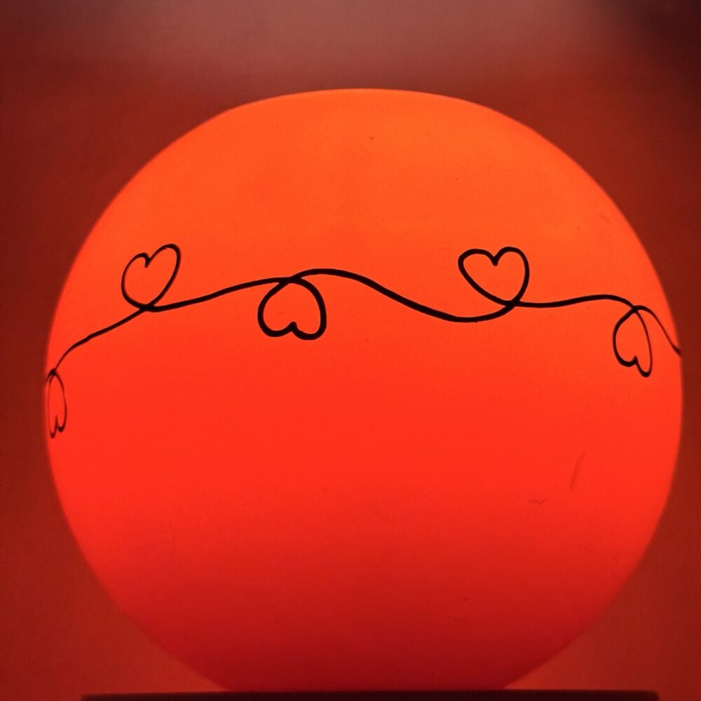 Photophore sphérique rouge à cœurs – cire minérale – 14 cm Photophore rouge en cire minérale avec motif de cœurs noirs, diamètre 14 cm