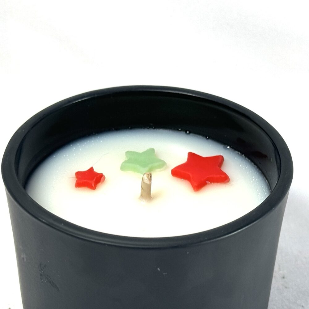 Bougie parfumée CONIFÊTES dans son pot, avec étoiles colorées visibles en surface avant fermeture