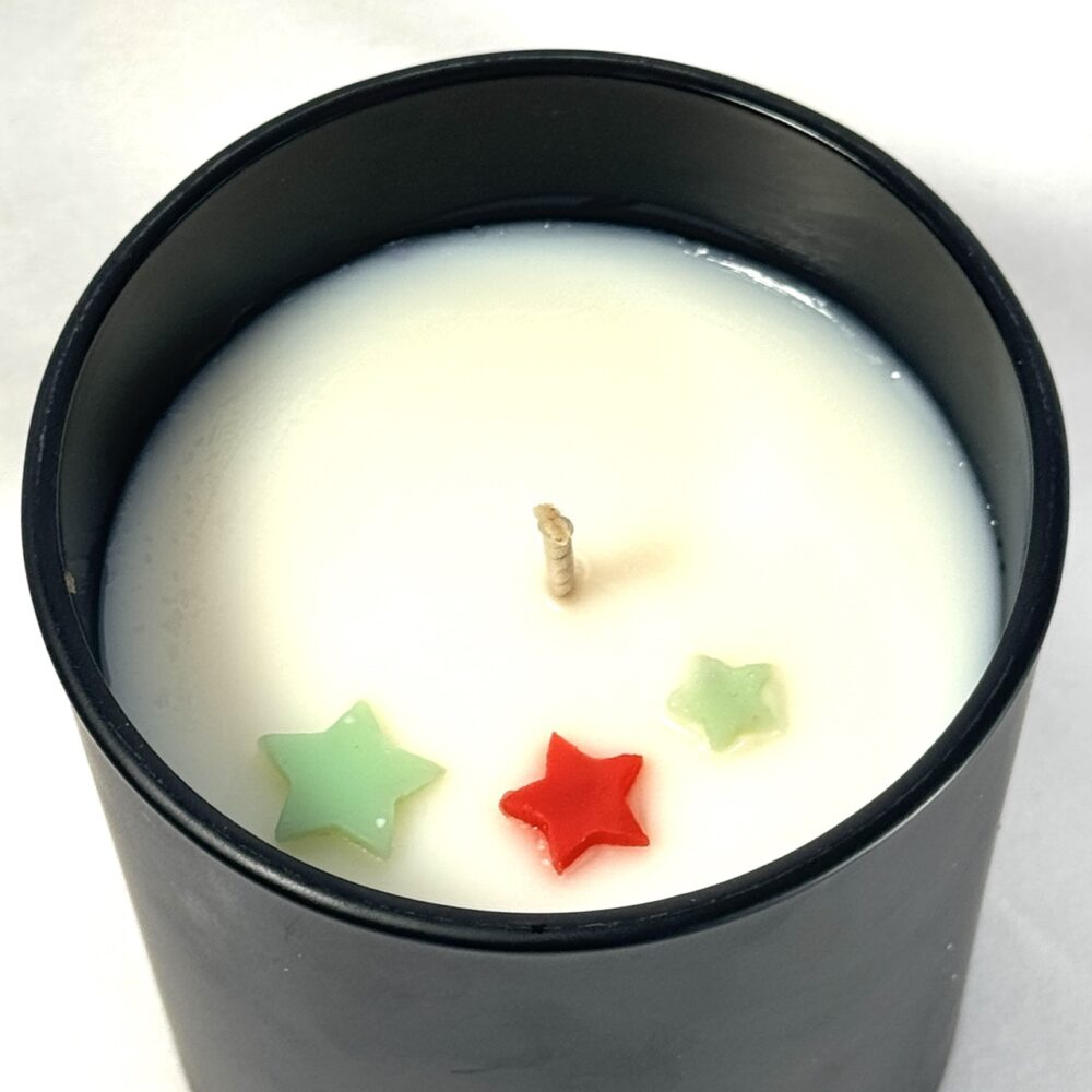 Bougie parfumée CONIFÊTES – vue du dessus – décoration étoiles Bougie parfumée CONIFÊTES dans son pot, avec étoiles colorées visibles en surface avant fermeture