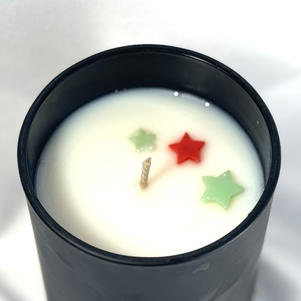 Bougie parfumée CONIFÊTES dans son pot, avec étoiles colorées visibles en surface avant fermeture