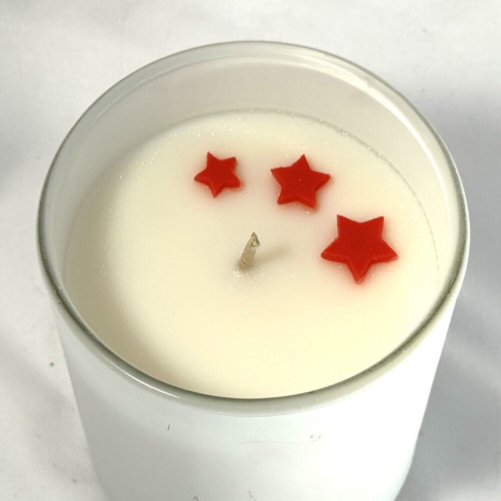 Bougie parfumée CONIFÊTES dans son pot, avec étoiles colorées visibles en surface avant fermeture