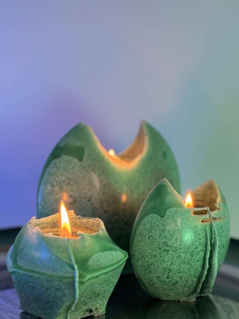 trois bougies en cire végétale allumées — tons vert de gris et vert profond