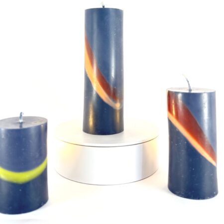 Trio de cylindres imparfaits en cire anthracite avec bandes colorées Trois bougies cylindriques en cire végétale teintée anthracite, traversées de bandes brun, orange et vert – série imparfaite et artisanale