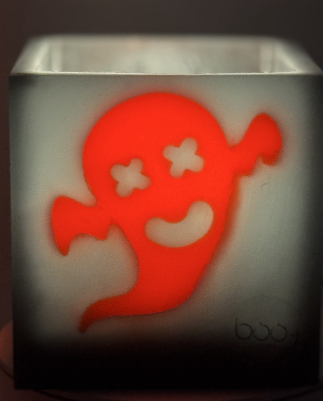 Photophore cube Halloween en cire gris foncé, décoré de quatre fantômes phosphorescents orange aux expressions variées — boo-j édition spectrale