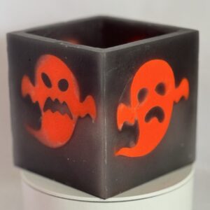 Photophore cube fantômes méchants phosphorescents — boo-j | édition spectrale Photophore cube Halloween en cire gris foncé, décoré de deux fantômes phosphorescents orange au visage méchant — boo-j édition spectrale