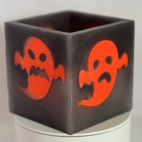 Photophore cube Halloween en cire gris foncé, décoré de deux fantômes phosphorescents orange au visage méchant — boo-j édition spectrale
