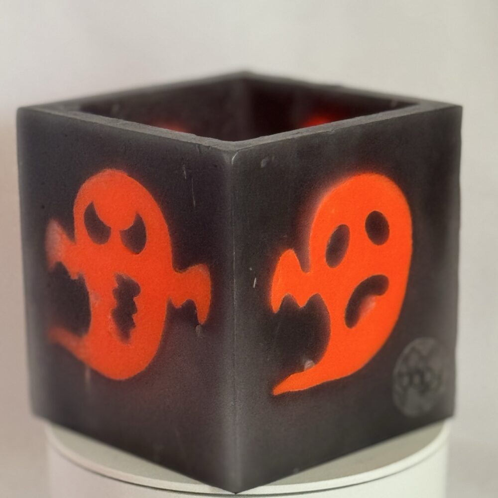 Photophore cube Halloween en cire gris foncé, décoré de deux fantômes phosphorescents orange au visage méchant — boo-j édition spectrale