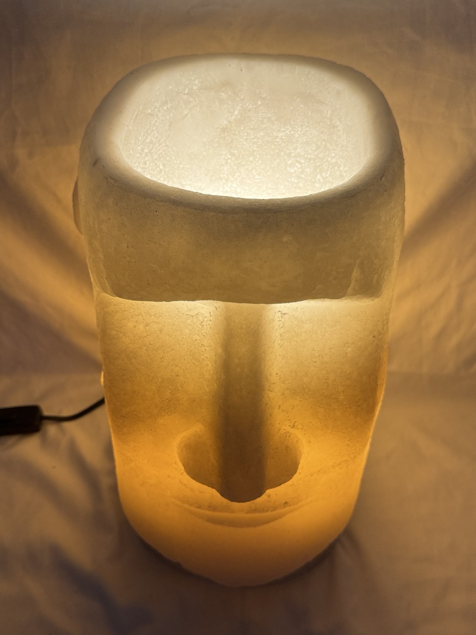 Photophore Moaï en cire recyclée éclairé de l’intérieur, vue de profil.