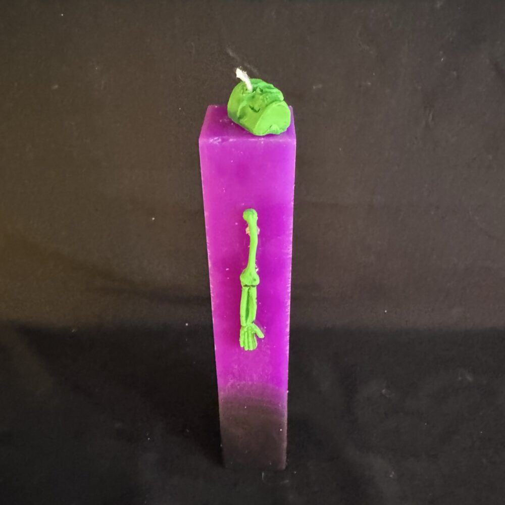 Bougie pilier Halloween violette en cire minérale et végétale, décorée d’un crâne et d’os en cire d’abeille vert fluo — création artisanale suisse boo-j, édition spectrale