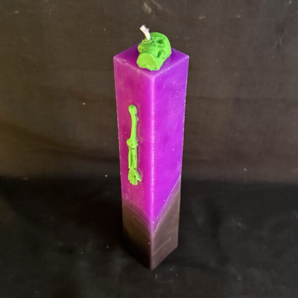 Bougie pilier Halloween violette en cire minérale et végétale, décorée d’un crâne et d’os en cire d’abeille vert fluo — création artisanale suisse boo-j, édition spectrale