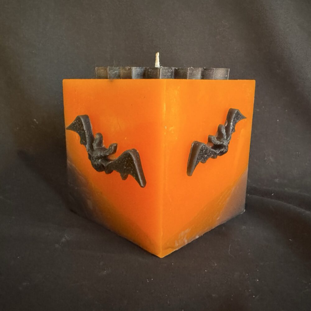 Bougie cubique Halloween de 10 cm, ± 700 g, en cire minérale et végétale orange avec chauves-souris en cire d’abeille noire — création artisanale suisse boo-j, édition spectrale