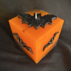 Bougie cube 10 cm Halloween — chauves-souris en cire d’abeille noire | boo-j édition spectrale Bougie cubique Halloween de 10 cm, ± 700 g, en cire minérale et végétale orange avec chauves-souris en cire d’abeille noire — création artisanale suisse boo-j, édition spectrale