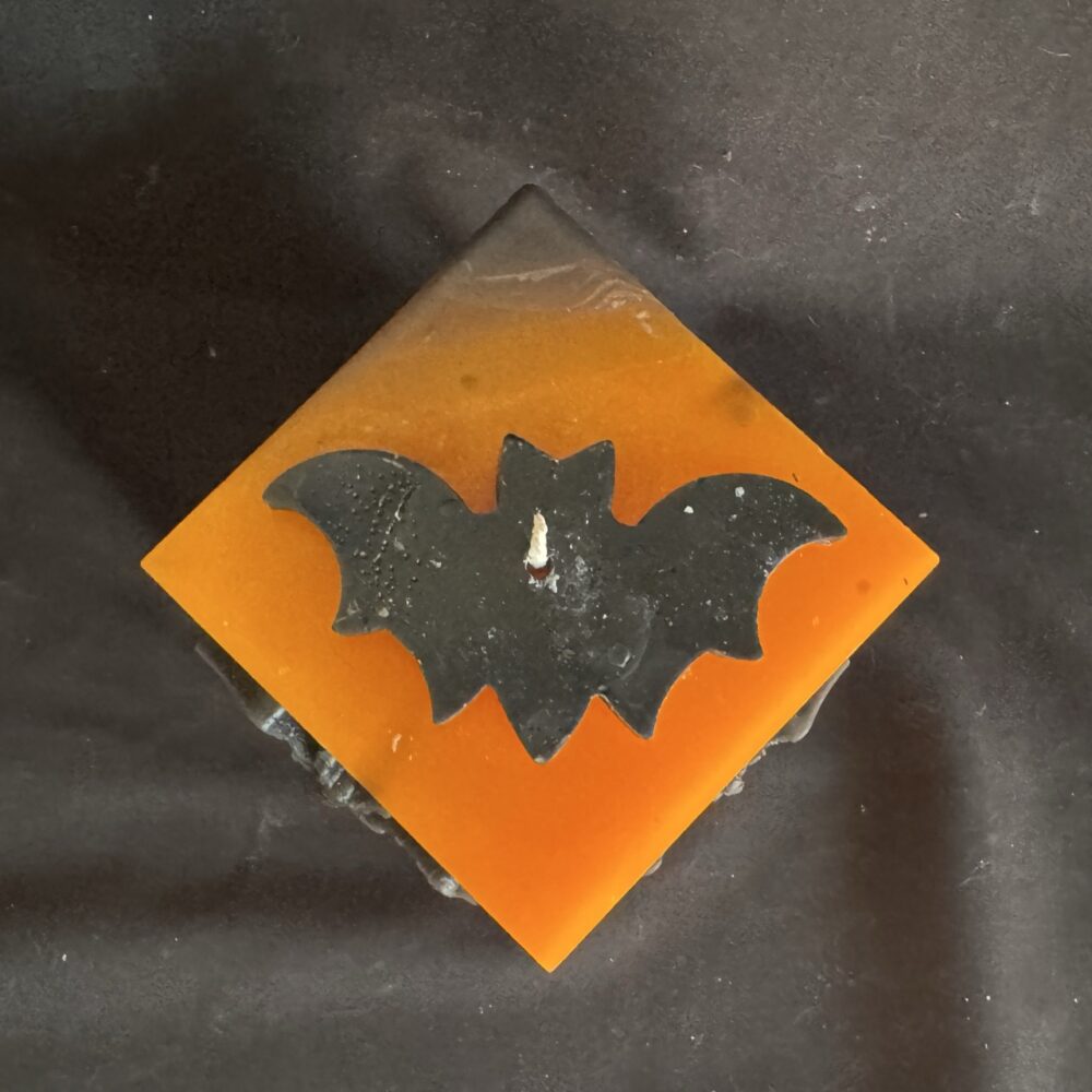 Bougie cubique Halloween de 10 cm, ± 700 g, en cire minérale et végétale orange avec chauves-souris en cire d’abeille noire — création artisanale suisse boo-j, édition spectrale