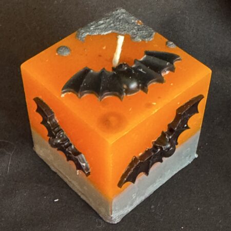 Bougie cube 5 cm Halloween — décorations en cire d’abeille noire | boo-j édition spectrale Bougie cubique Halloween de 5 cm, environ 120 g, en cire minérale et végétale orange, décorée de chauves-souris en cire d’abeille noire — création artisanale suisse boo-j, édition spectrale