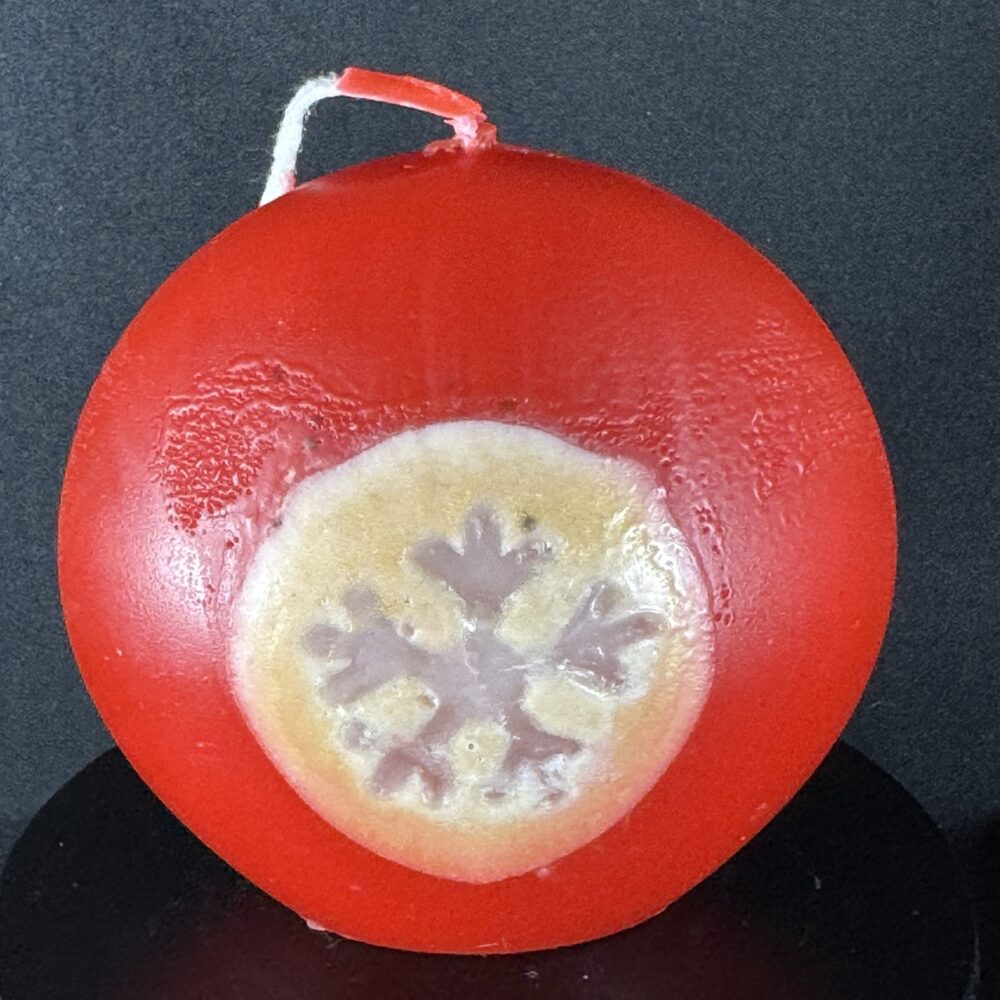 Bougie artisanale rouge et dorée de 10 cm avec motif central de flocon blanc, coulée à la main en cire minérale et végétale. Création boo-j réalisée dans le canton de Vaud.