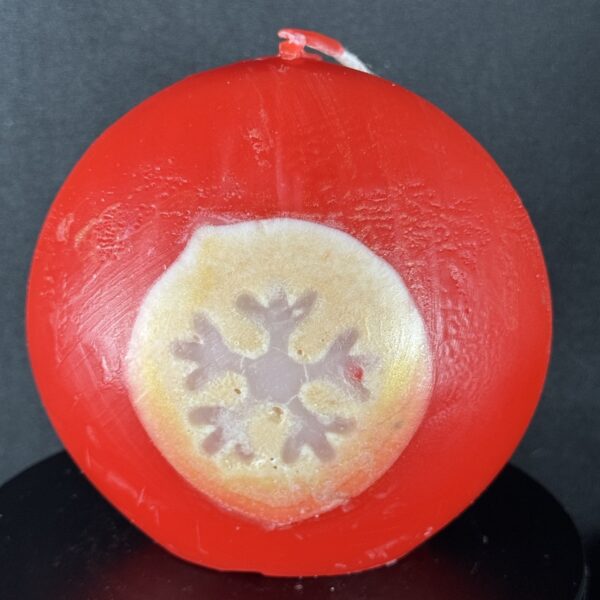 Bougie artisanale rouge et dorée de 10 cm avec motif central de flocon blanc, coulée à la main en cire minérale et végétale. Création boo-j réalisée dans le canton de Vaud.