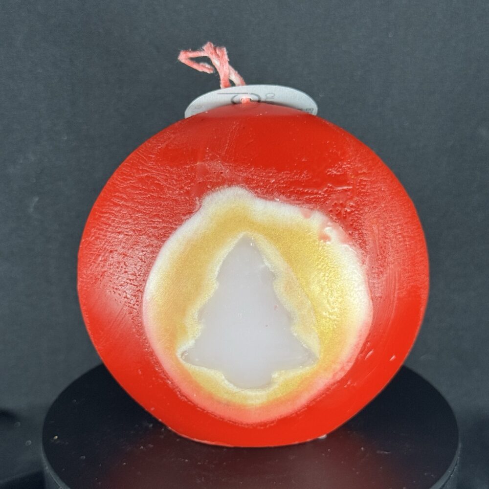 Bougie artisanale rouge et dorée de 10 cm avec motif central de sapin blanc, coulée à la main en cire minérale et végétale. Création boo-j, fabriquée dans le canton de Vaud.