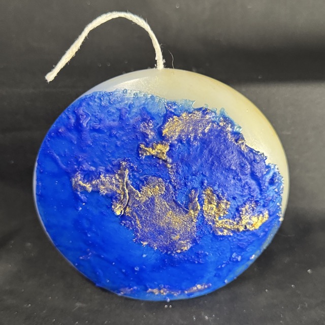 Bougie disque 14 cm de la collection Nuit Étoilée, en cire minérale et végétale blanche, avec finition bleu outremer et dorures à la main. Création artisanale boo-j, environ 520 g, combustion ± 50 h.