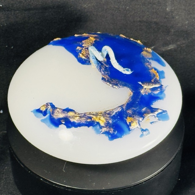 Bougie soucoupe 12,5 × 6 cm de la collection Nuit Étoilée, en cire minérale et végétale blanche avec finitions bleu outremer et dorures appliquées à la main. Création artisanale boo-j, env. 370 g, combustion ± 15 h.