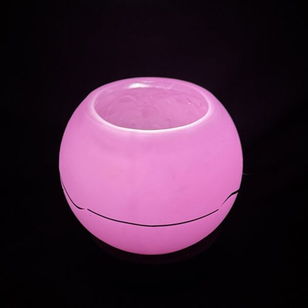 Photophore sphérique rose en cire minérale translucide, décoré d’un motif de vagues noires, fait main dans le canton de Vaud.