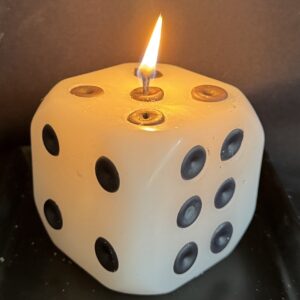 Bougie artisanale en forme de dé, 8×8×8 cm, environ 440 g, réalisée à la main en cire mixte végétale et minérale. Photo prise lors de la combustion, création boo-j faite en Suisse.