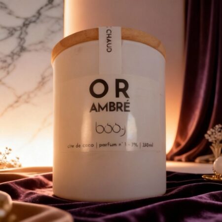 Bougie parfumée artisanale BOO-J aux notes d'ambre, dans un pot aux reflets dorés, posée sur un fond neutre