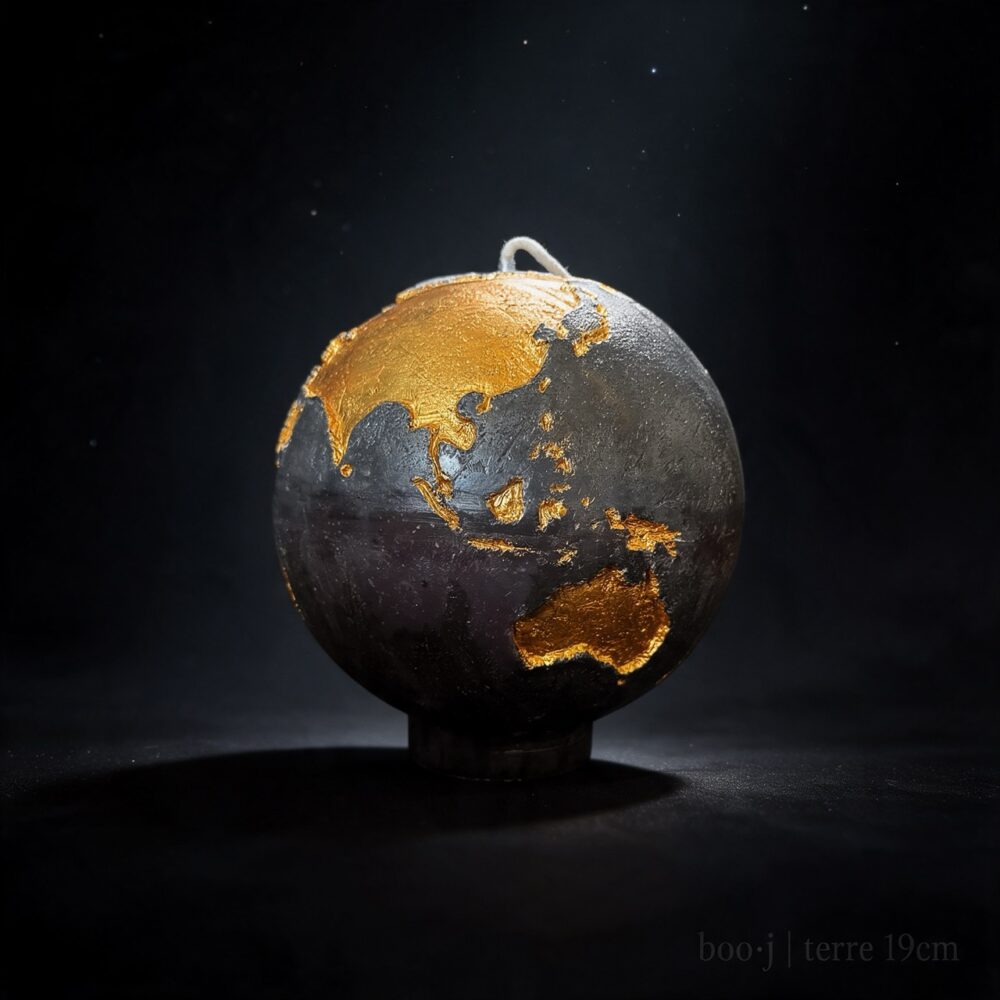 Grande bougie sphérique exclusive boo·j de 19 cm, fait main, représentant la Terre noire avec continents en couleur or foncé, pièce maîtresse de la collection.