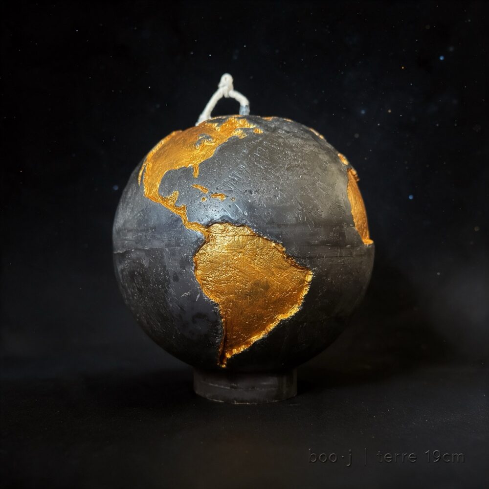 Grande bougie sphérique exclusive boo·j de 19 cm, fait main, représentant la Terre noire avec continents en couleur or foncé, pièce maîtresse de la collection.