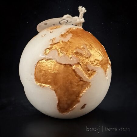 Bougie sphérique exclusive boo·j de 8 cm, fait main, représentant la Terre avec continents en or foncé sur fond blanc.