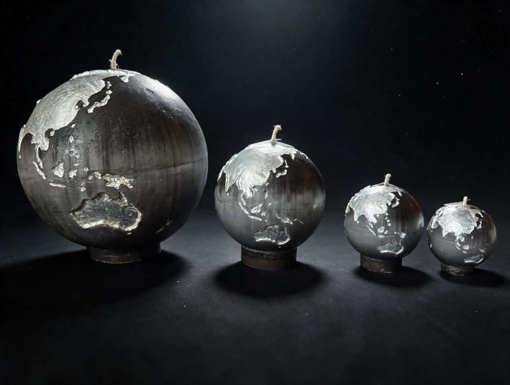 Collection de quatre bougies sphère Terre boo·j en noir anthracite dégradé gris, aux continents blancs irisés, en 19, 12, 8 et 6 cm