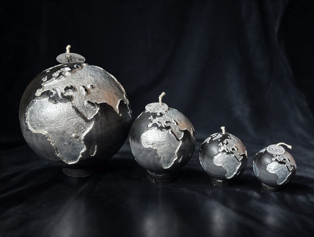 Collection de quatre bougies sphère Terre boo·j en noir anthracite dégradé gris, aux continents blancs irisés, en 19, 12, 8 et 6 cm